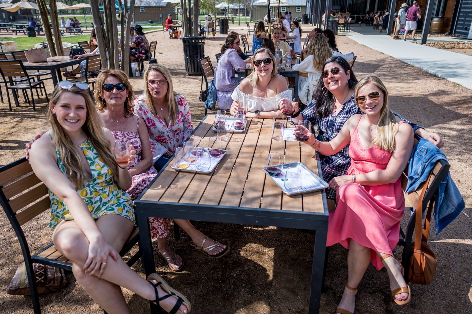 A tour group gathered around a long patio table with tasting flights